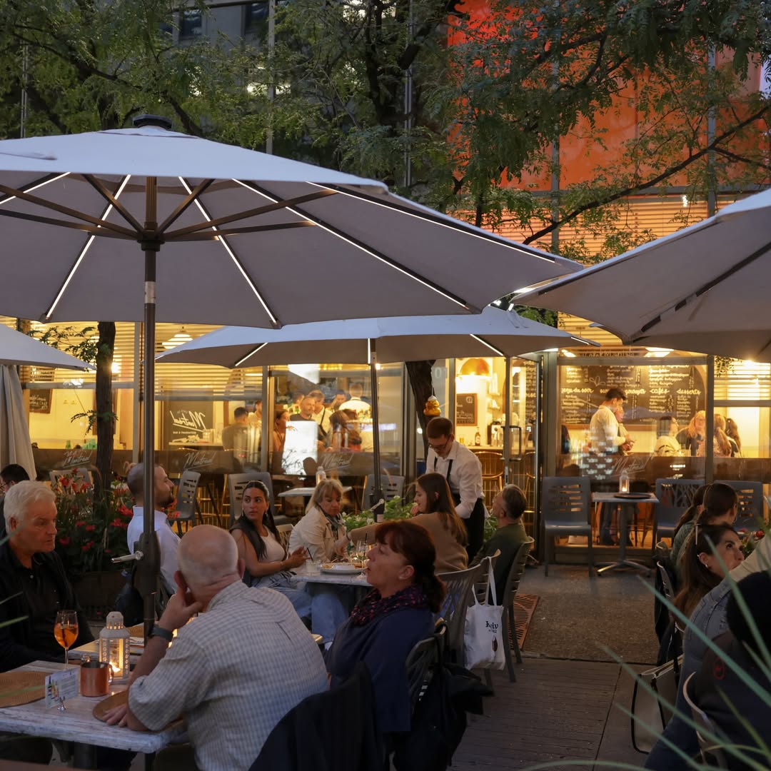 Soirée animée en terrasse au Café de Montréal, sous de grands parasols, ambiance chaleureuse et cuisine conviviale au cœur du centre-ville.