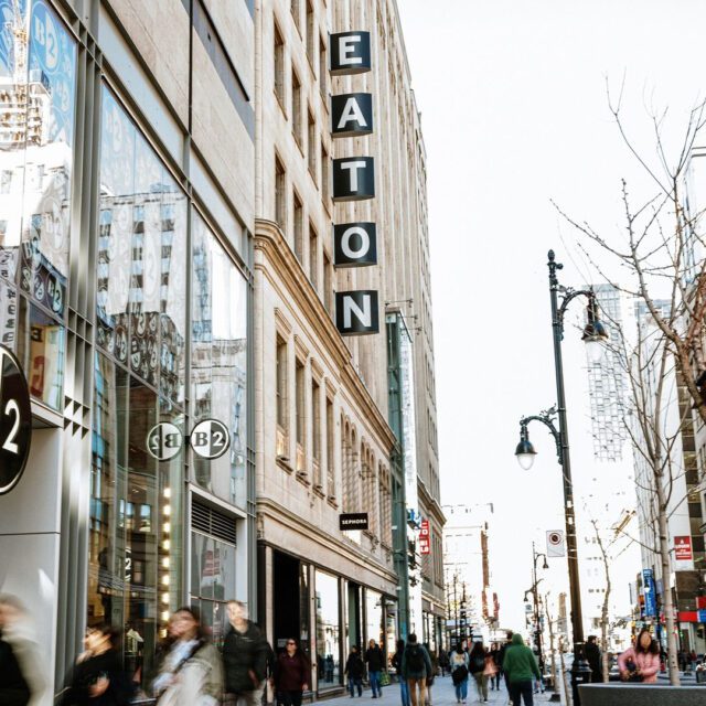 Centre Eaton entrance on Sainte-Catherine Street, downtown Montreal, with pedestrians and store signs.