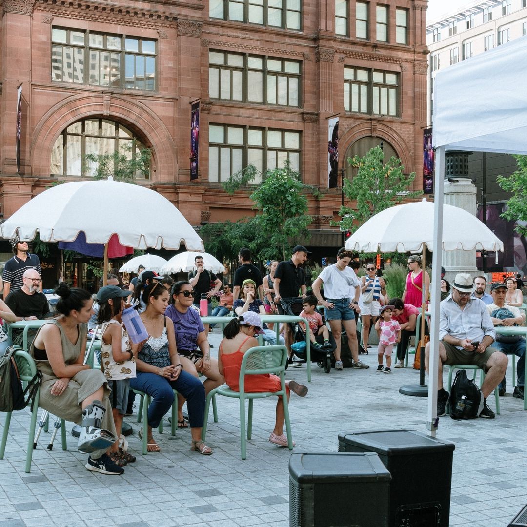 Familles et amis profitant d'un concert gratuit en plein air au square Philips, centre-ville de Montréal.