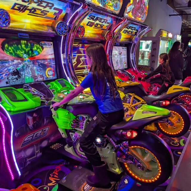Enfant participant à une course de motos dans une salle d’arcades chez Mira Amusement au MTL Forum à Montreal.