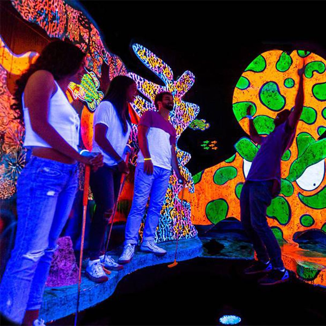 People playing glow-in-the-dark mini-golf at Putting Edge, Montreal.