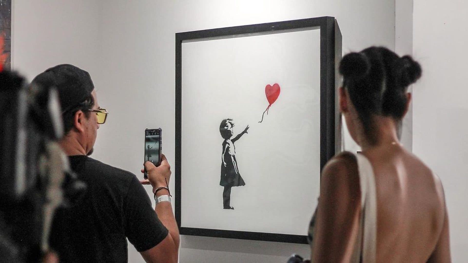 Visiteurs admirant l'œuvre iconique de Banksy, La Fille au Ballon Rouge, lors de d'une exposition immersive