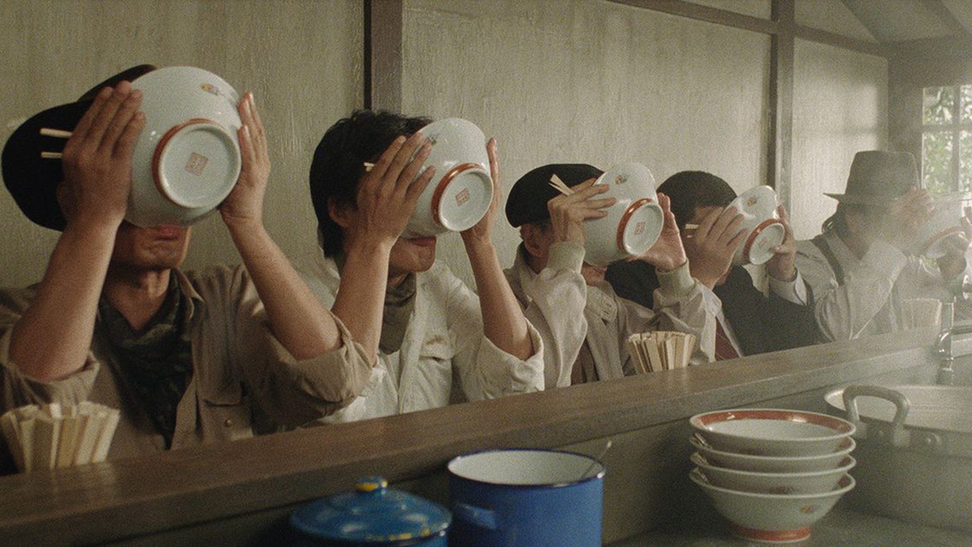 Group of people enjoying a bowl of ramen in a restaurant.