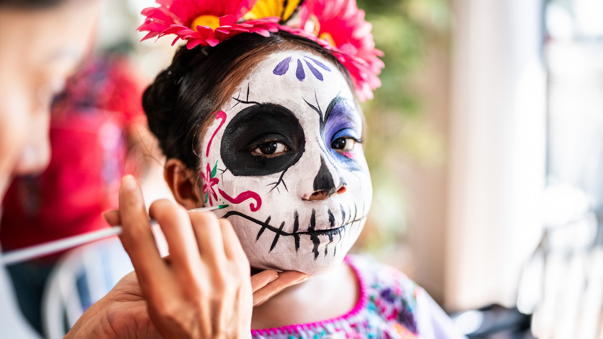 Child with traditional Dia de los Muertos face paint during a celebration at Montreal's Centre Eaton.