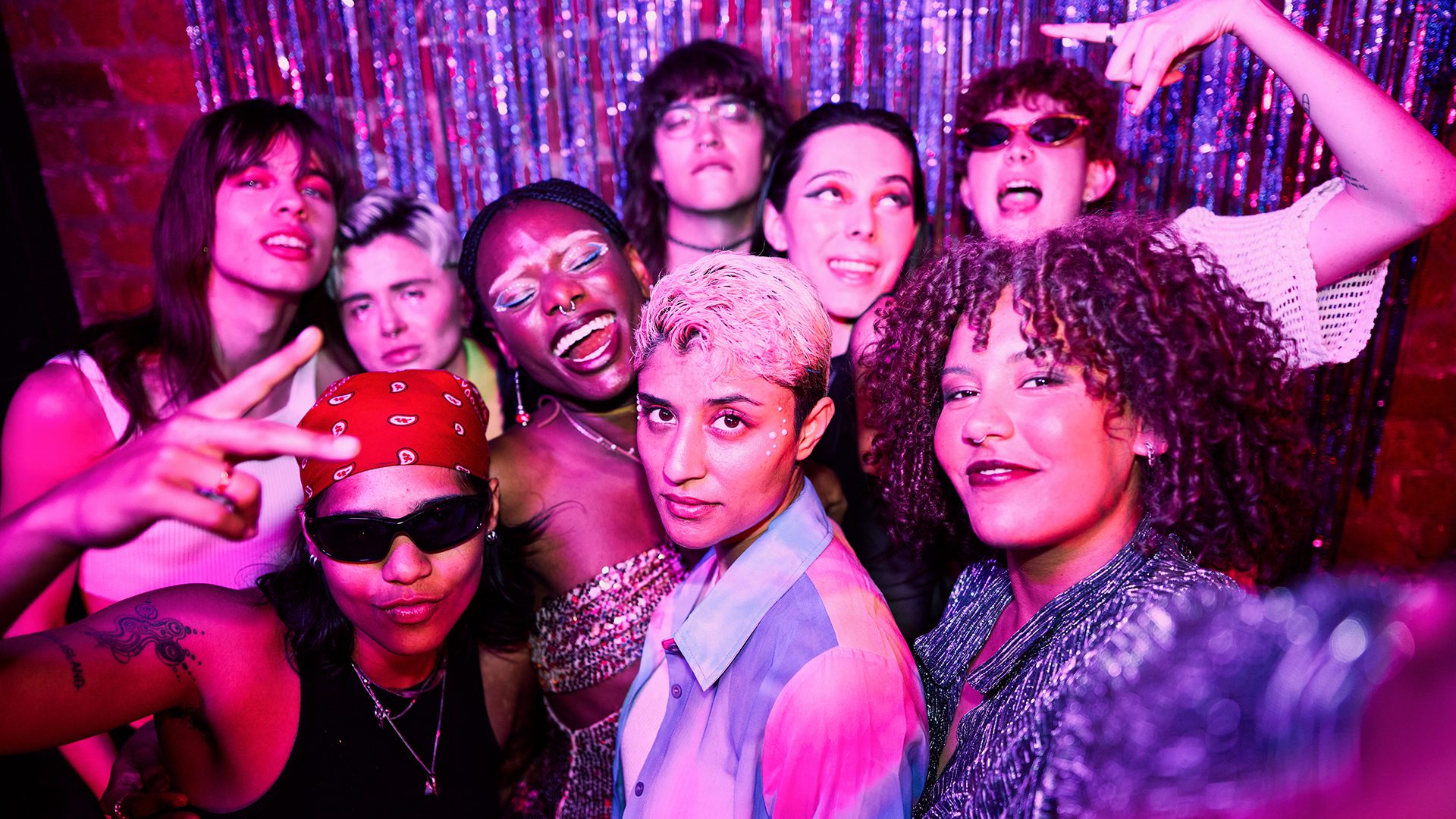 Group of people in hip hop costumes under colorful lights at a party.