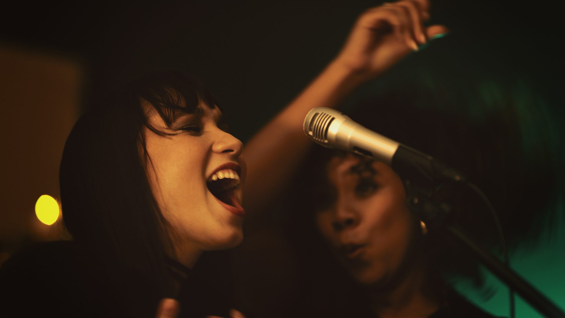 Women singing into a microphone during karaoke at Piranha Bar.