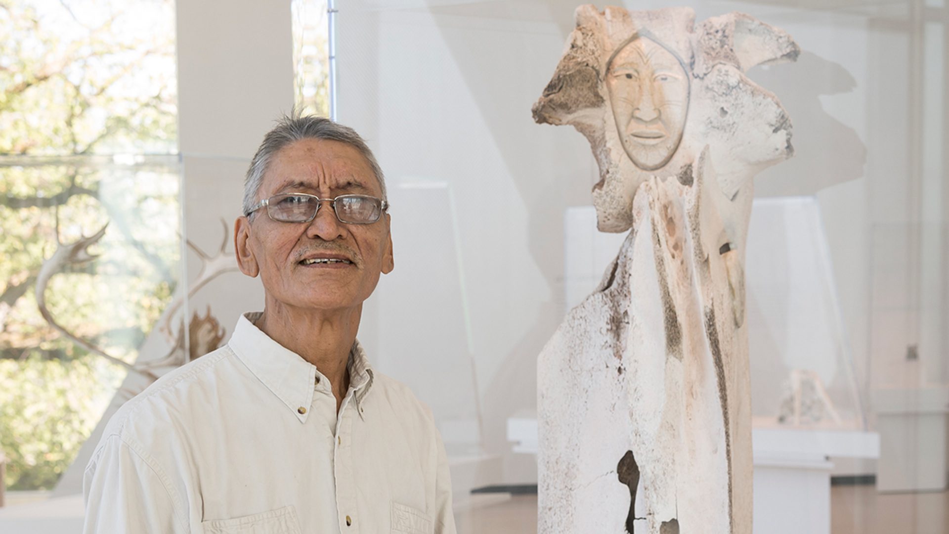 Manasie Akpaliapik avec une de ses sculptures en os de baleine au Musée McCord Stewart.