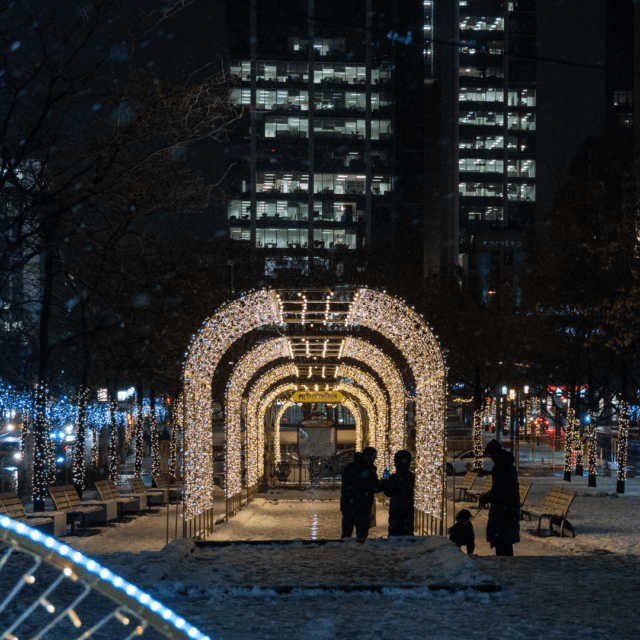 Gens qui marchent à travers les illuminations du centre-ville de Montréal au Square Victoria