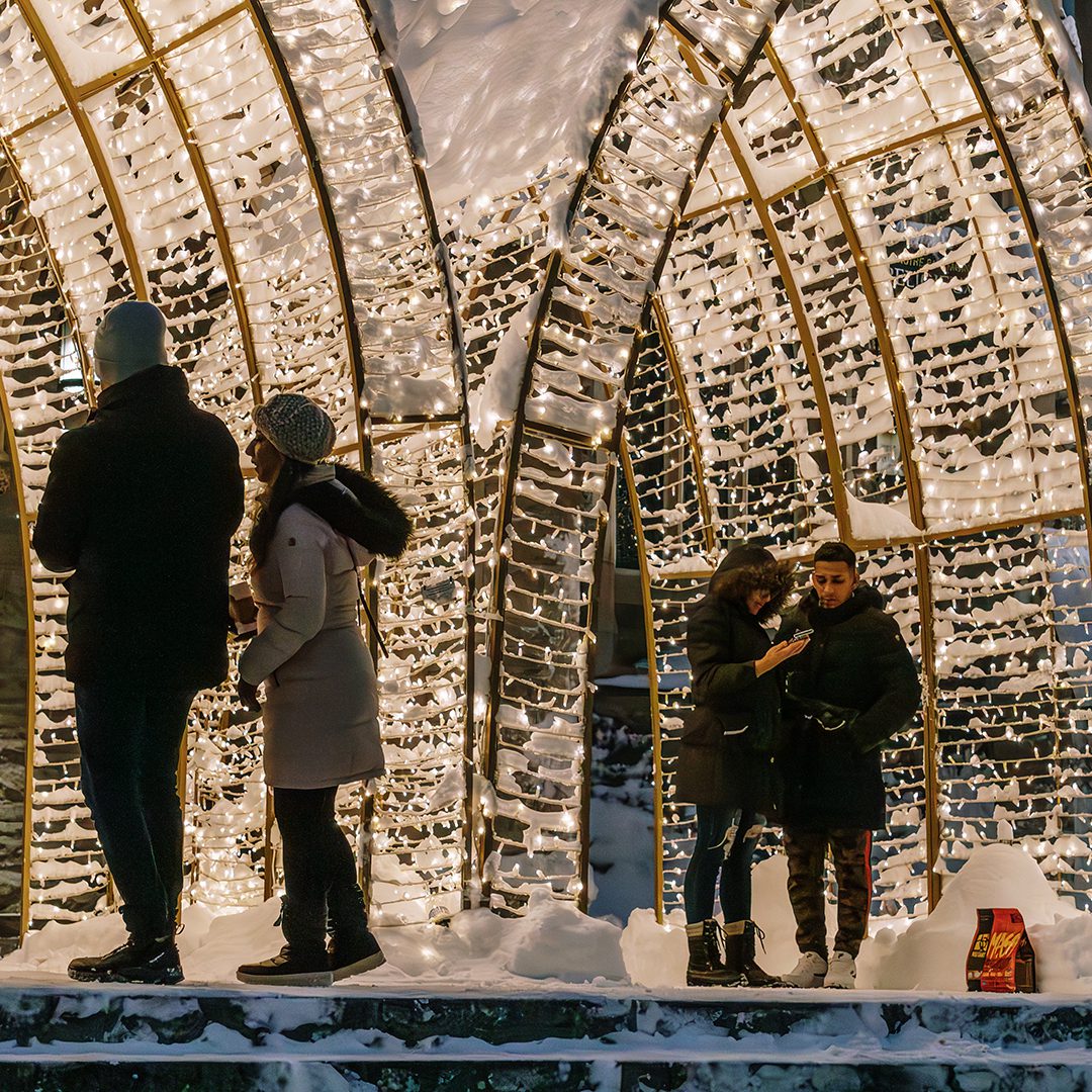 Groupe de personnes sous des arches illuminées à Montréal, parfait pour une sortie hivernale féerique.