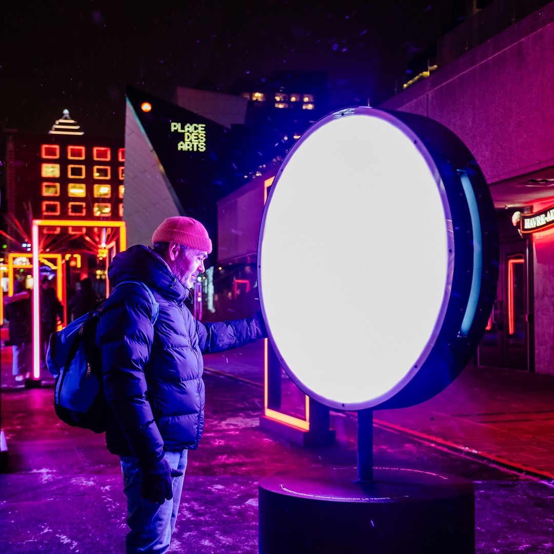 Homme touchant un cercle lumineux interactif à la Place des Arts