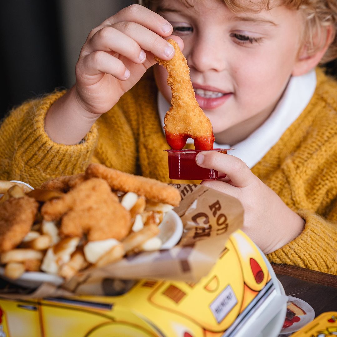 Enfant savourant du poulet et des frites au St-Hubert, restaurant familial.