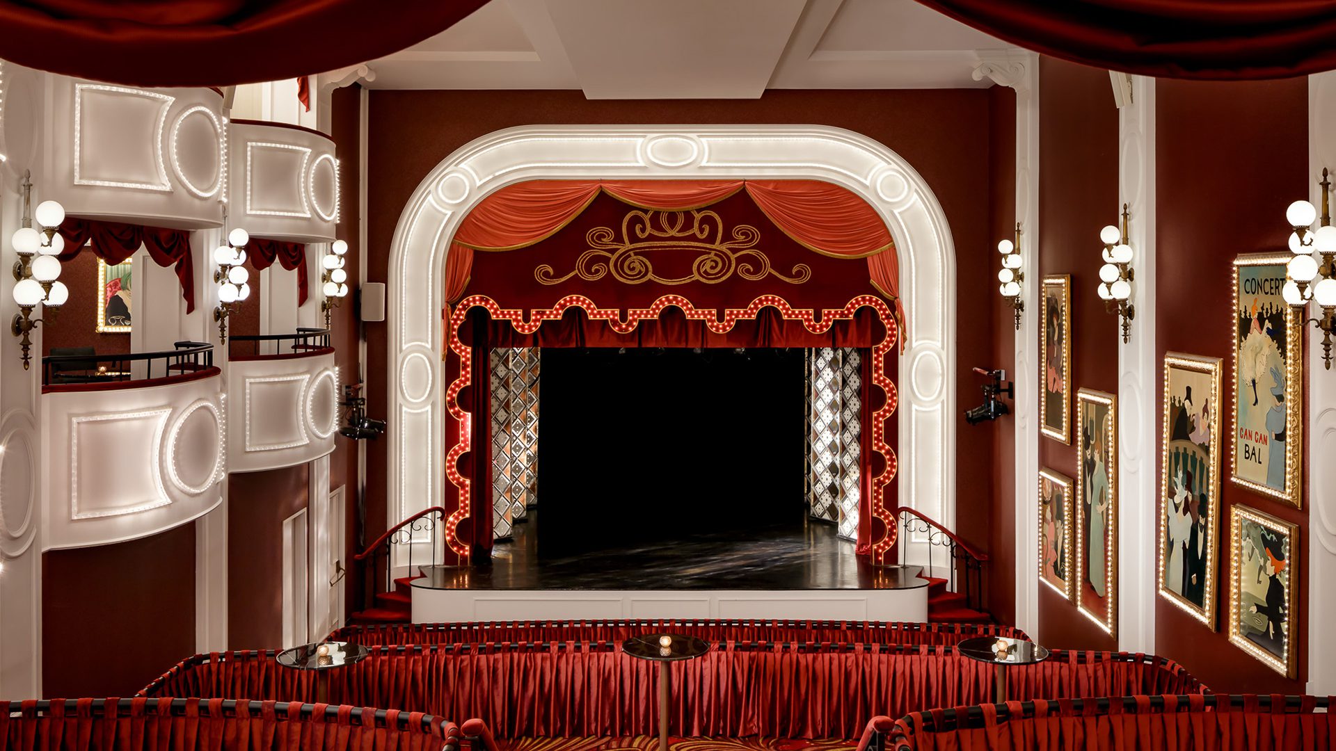 Intérieur d'un théâtre élégant avec rideaux rouges, balcons et scène ornée de lumières