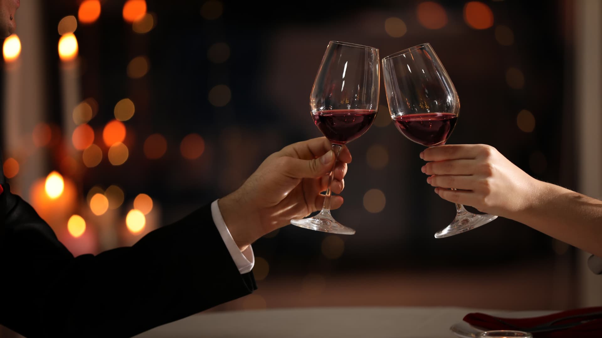 Deux verres de vin rouge trinquant dans une ambiance romantique.