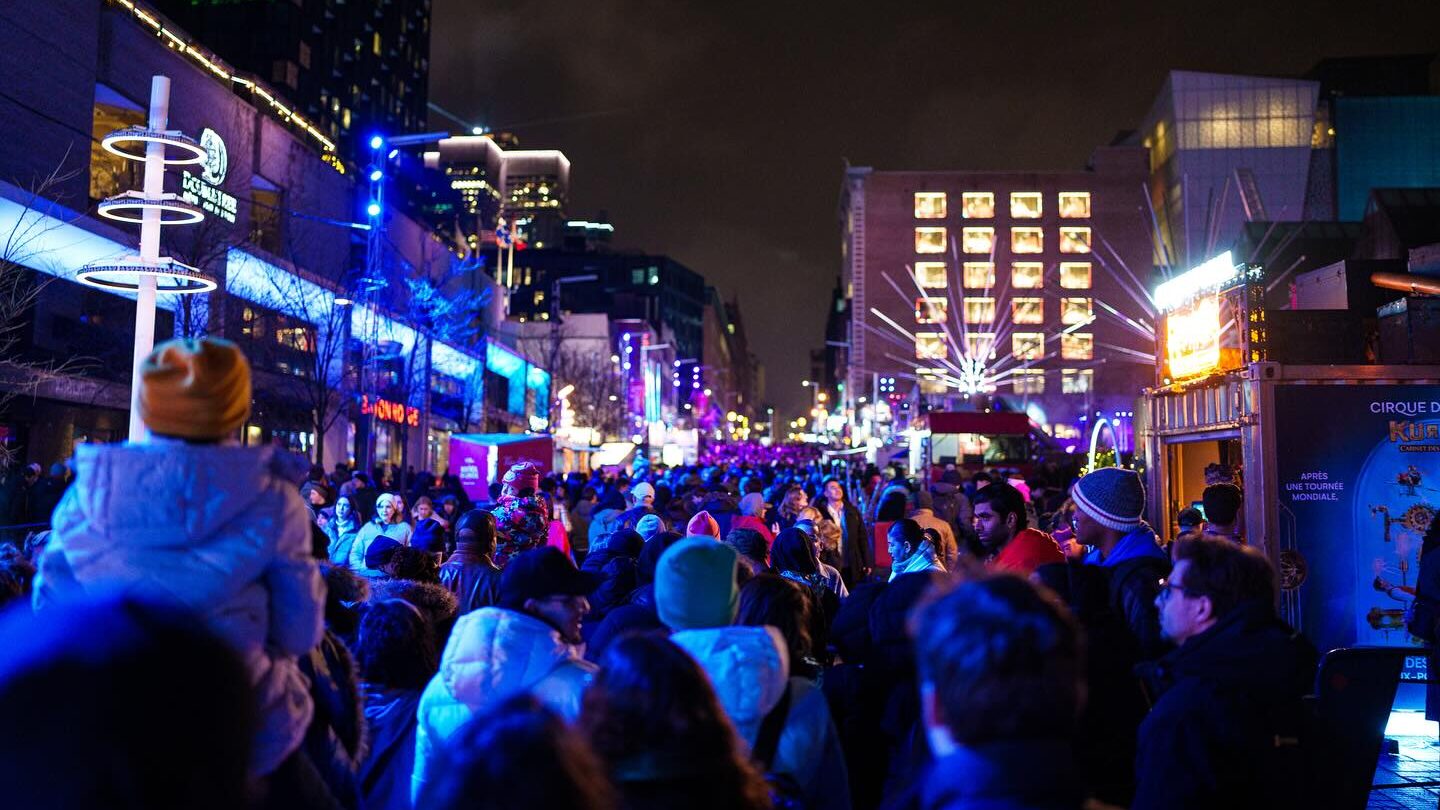 Lively crowd at Nuit blanche à Montréal in the Quartier des spectacles, illuminated by vibrant light installations and a festive atmosphere.