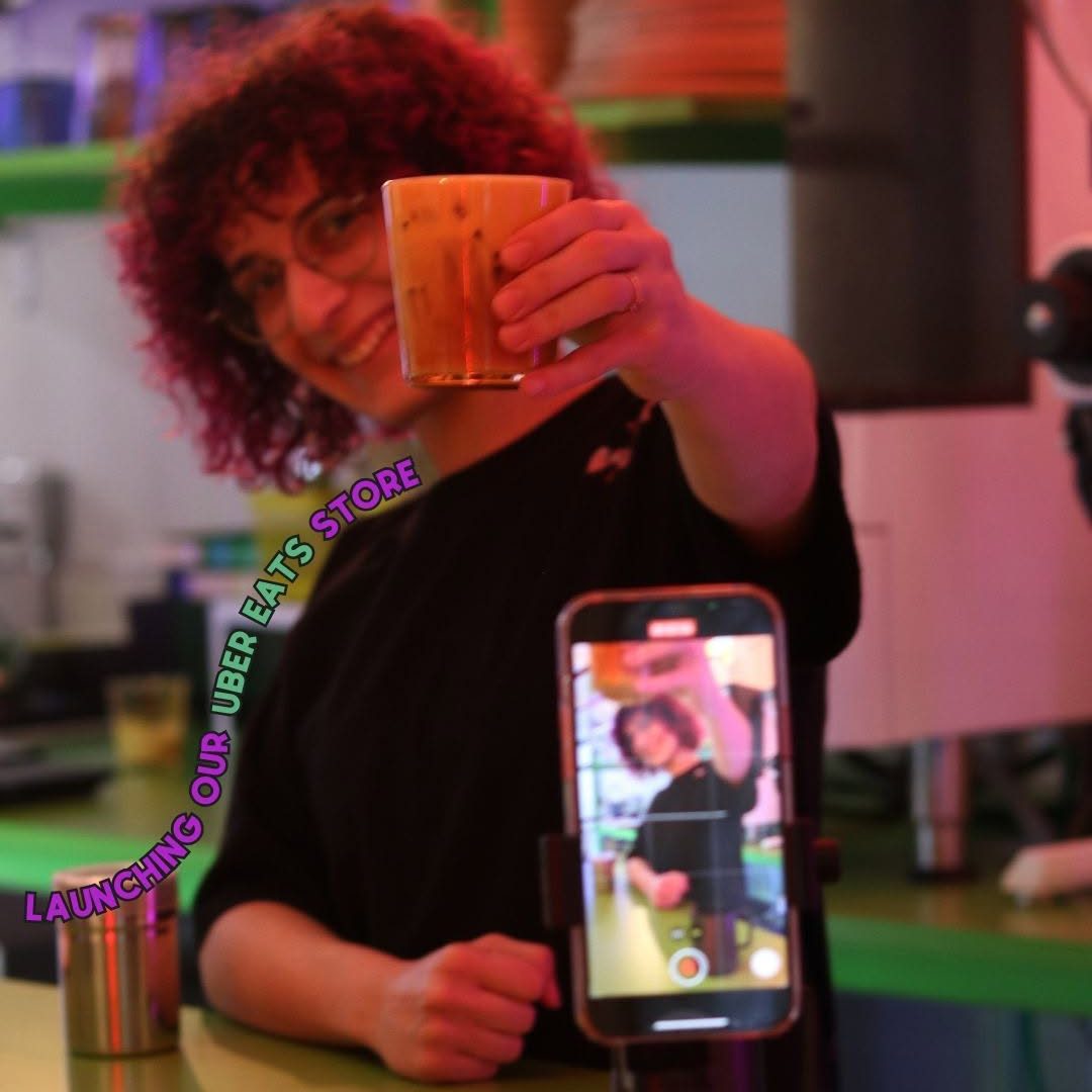 Sara Neji raising her glass, captured on video in the vibrant and lively atmosphere of Kaizen Manga Café.