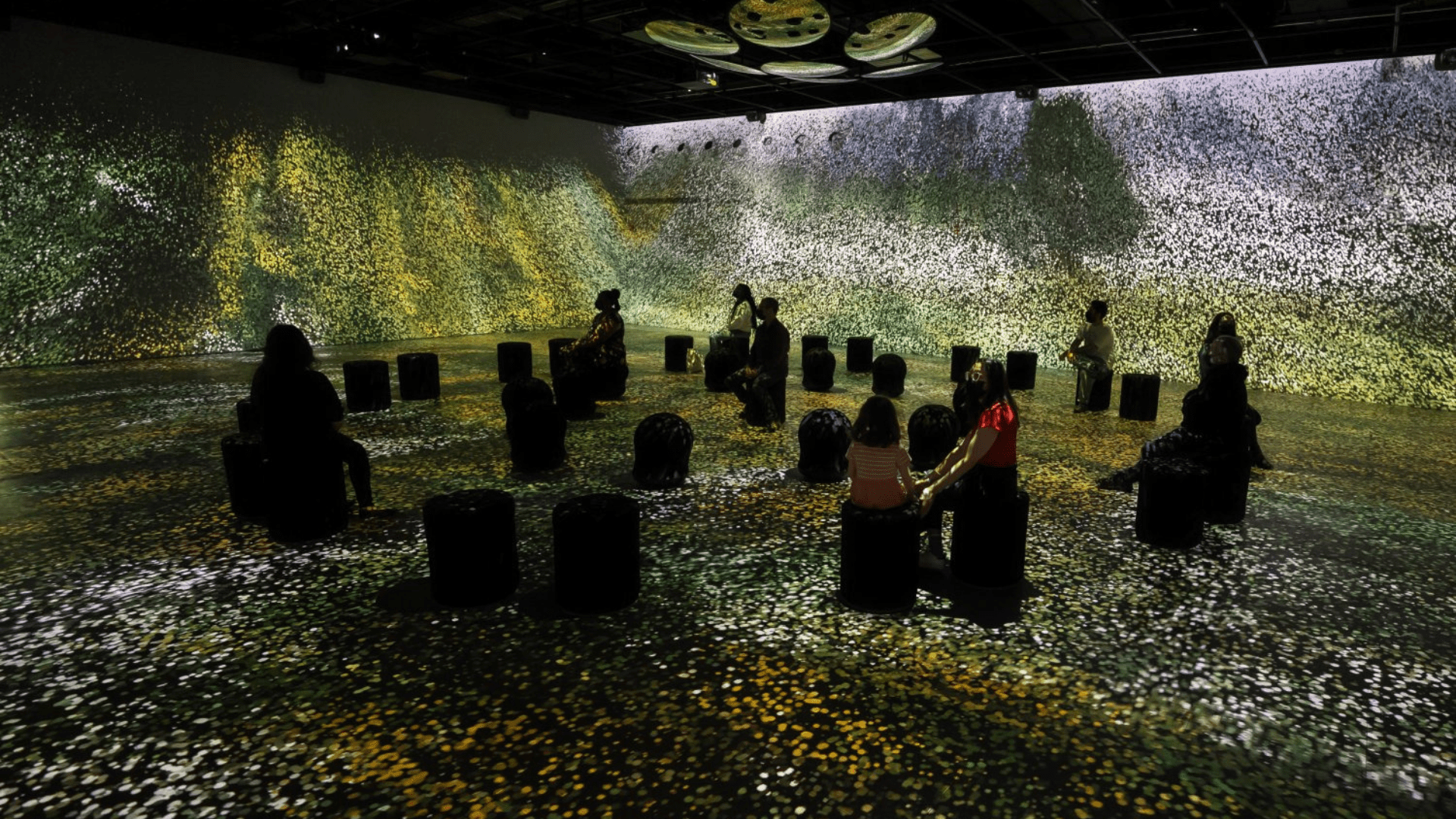 Salle immersive de l'exposition Van Gogh – Distorsion à OASIS, avec projections lumineuses et visiteurs assis.