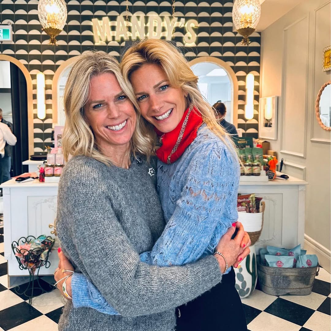 The founders of Mandy’s, smiling and embracing in front of their iconic sign, surrounded by a chic and inviting decor.