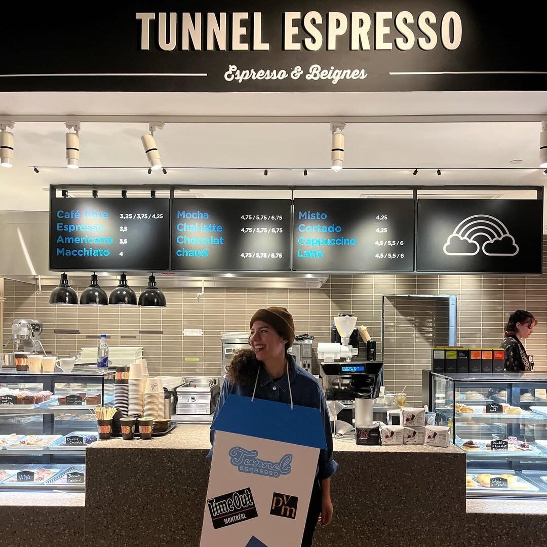 Elsa Ouagmi devant le comptoir de Tunnel Espresso au Time Out Market, portant un costume en forme de carton de lait.