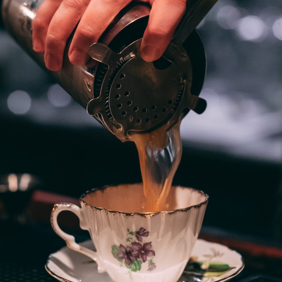 Cocktail ambré versé dans une tasse en porcelaine vintage.