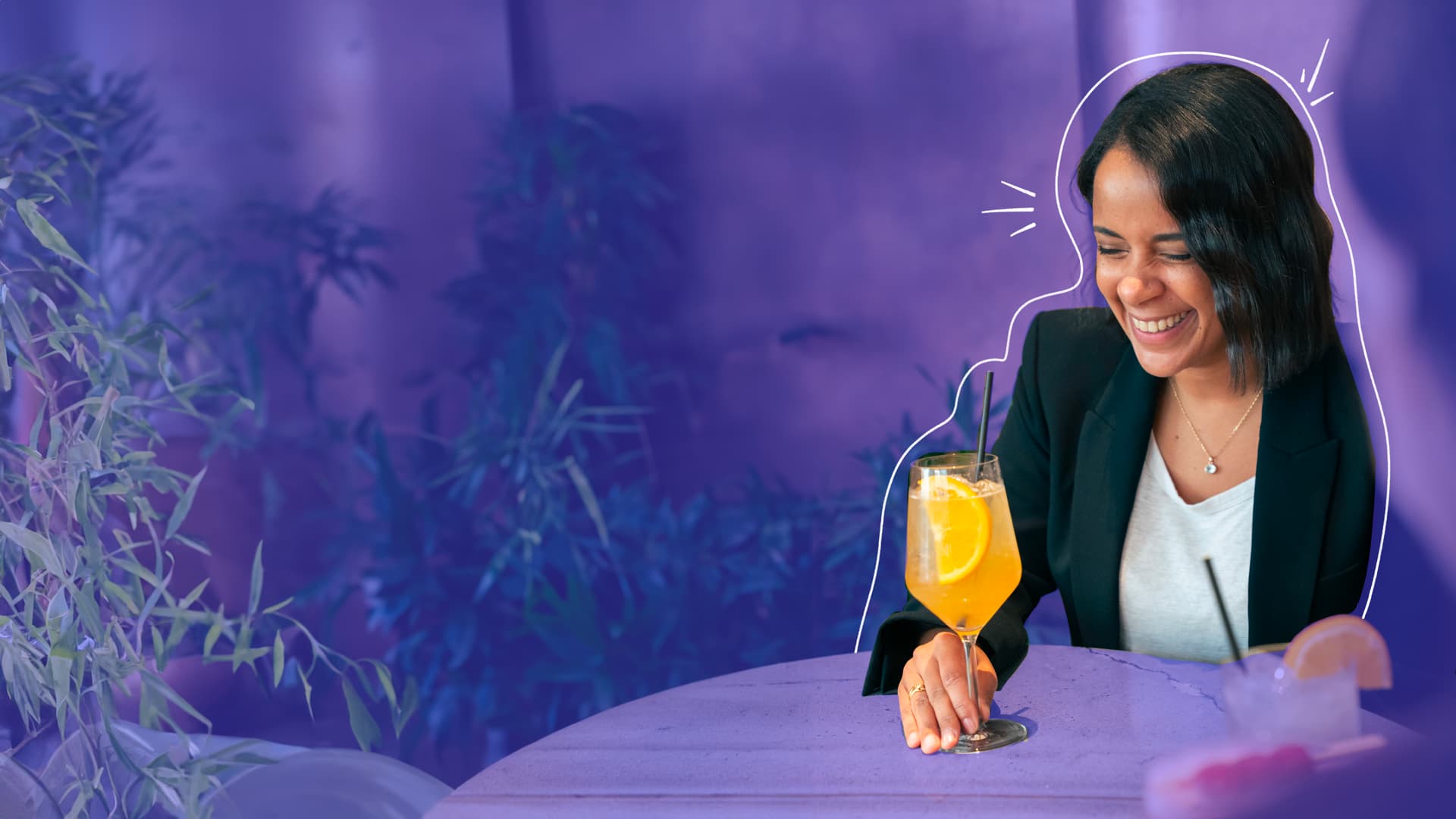 Une femme regarde son cocktail avec un sourire
