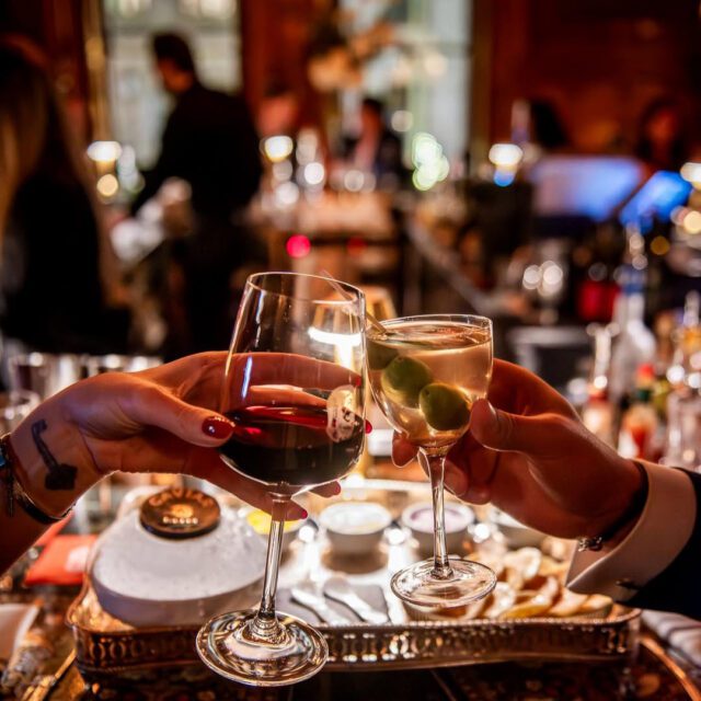 Verres qui trinquent au Bar George, dans une ambiance élégante.