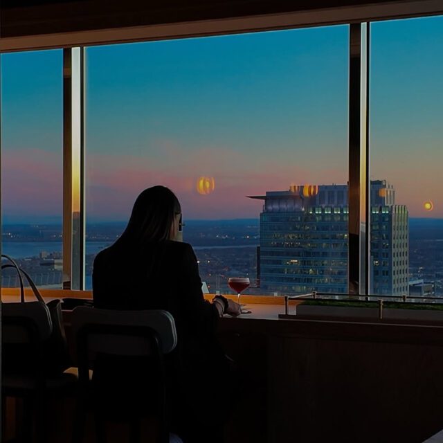 Femme qui boit un espresso martini avec vue sur le centre-ville de Montréal au Sora45